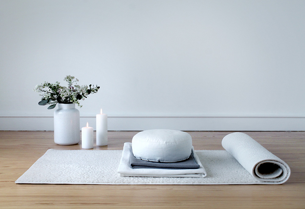 Yogamatte mit Kissen, Kerzen und Blumenstrauß